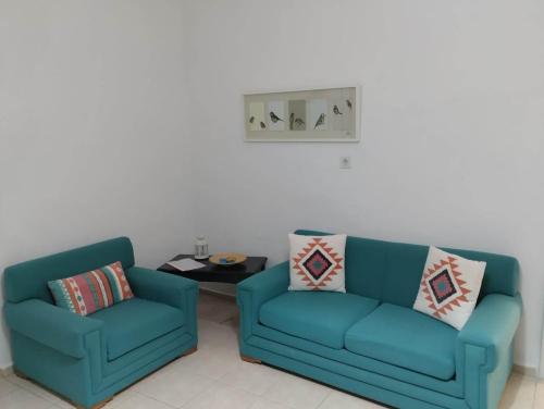 two blue chairs and a table in a living room at Emmanuela House with garden & sea view - Triopetra in Triopetra