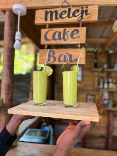 a person holding a tray with two drinks on it at Meleji Studio House in Arusha