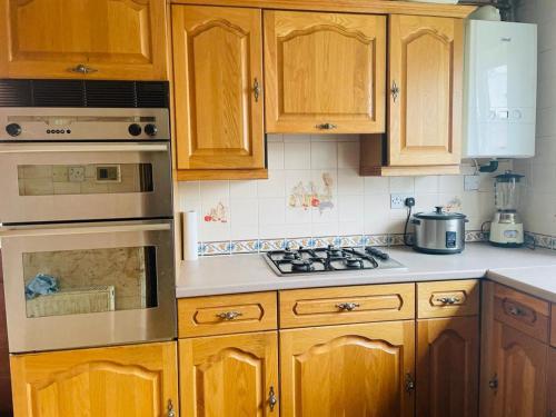 a kitchen with wooden cabinets and a stove top oven at Rowan House Rotherham in Rotherham