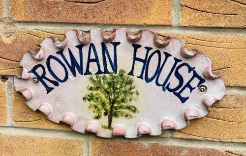 a sign on a brick wall with a tree on it at Rowan House Rotherham in Rotherham