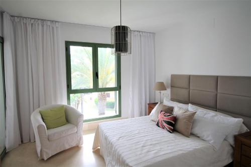 um quarto com uma cama, uma cadeira e uma janela em New view Sotogrande Marina - Jungla del Loro em Sotogrande