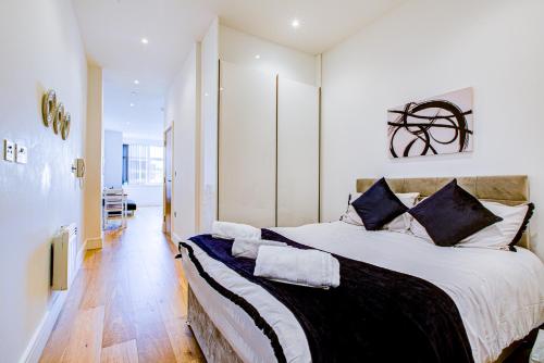 ein Schlafzimmer mit einem großen Bett mit schwarzen und weißen Kissen in der Unterkunft The Landmark, Lutons best location in Luton