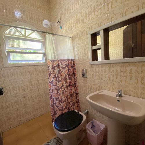 a bathroom with a toilet and a sink at Chácara Palma in Ubatuba