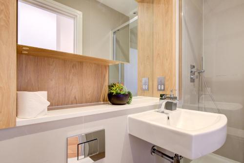 a white bathroom with a sink and a mirror at The Landmark, Lutons best location in Luton