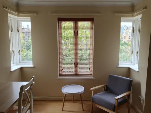 a room with a table and a chair and windows at Spacious Room in Leafy, Quiet N4 in London