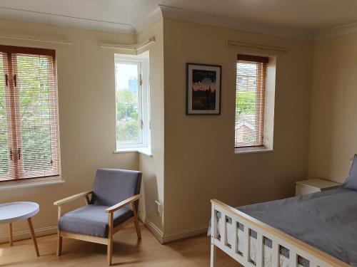 een slaapkamer met een bed, een stoel en ramen bij Spacious Room in Leafy, Quiet N4 in Londen