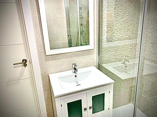 La salle de bains est pourvue d'un lavabo blanc et d'une douche. dans l'établissement BENALBEACH GARDEN, à Benalmádena