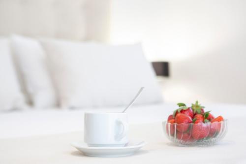 a bowl of strawberries next to a cup of coffee at Adria Luxury Apartments in Nydri