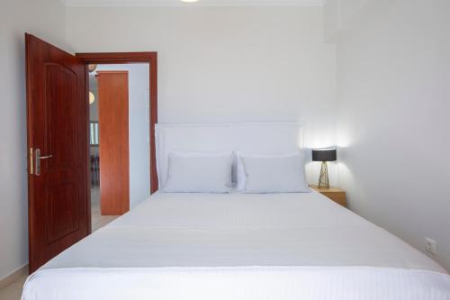 a bedroom with a large white bed with a wooden door at Adria Luxury Apartments in Nydri