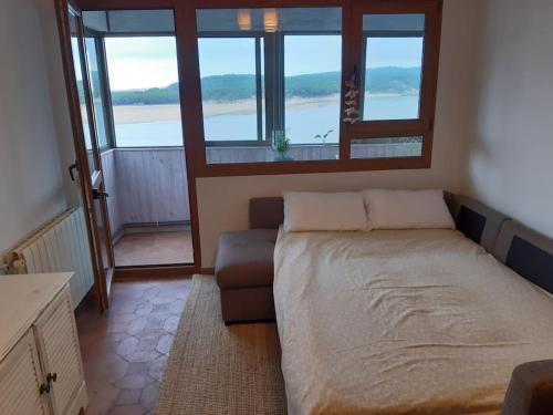 a bedroom with a bed and a couch and windows at Santander Mogro in Mogro