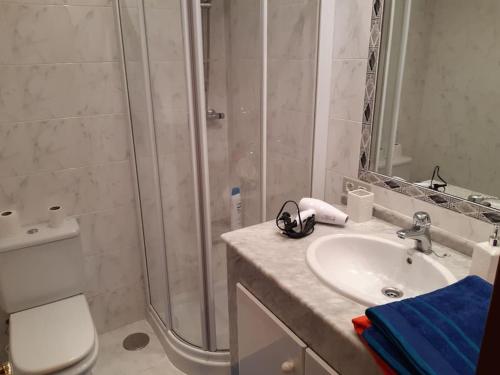 een badkamer met een douche, een wastafel en een toilet bij Santander Mogro in Mogro