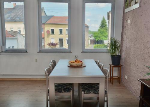 einen Tisch mit einer Obstschale darauf in einem Zimmer mit Fenstern in der Unterkunft Studio in Wehingen in Mettlach