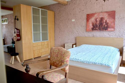 ein Schlafzimmer mit einem Bett und einem Stuhl darin in der Unterkunft Studio in Wehingen in Mettlach