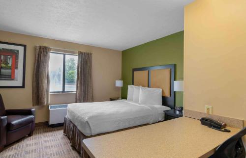a hotel room with a bed and a chair at Suburban Studios Louisville East in Louisville