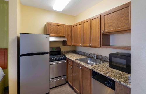 a kitchen with a white refrigerator and wooden cabinets at Extended Stay America Suites - Virginia Beach in Virginia Beach