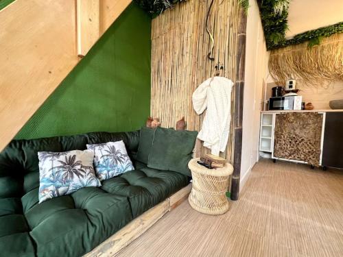 - un canapé vert dans une pièce dotée d'un mur vert dans l'établissement Nuit dans la jungle - love room, à Souppes-sur-Loing