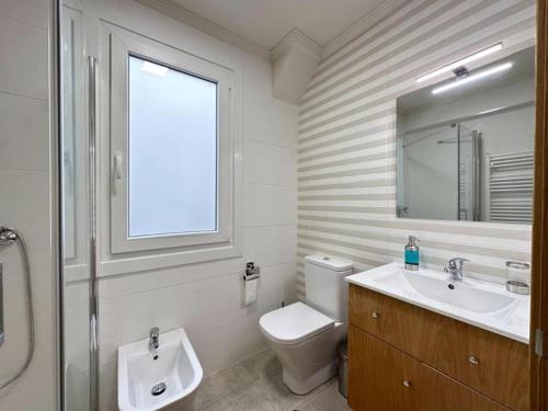 ein Bad mit einem Waschbecken, einem WC und einem Fenster in der Unterkunft Amplio apartamento con terraza en Bouzas, cerca de la playa. in Vigo