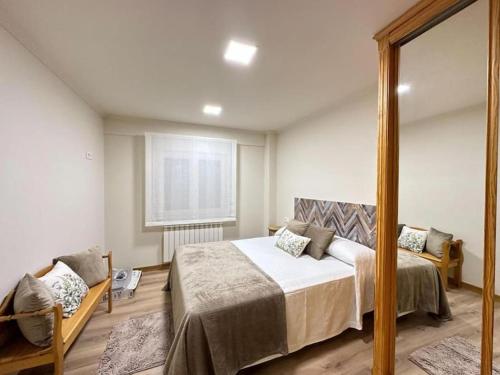 ein Schlafzimmer mit einem großen Bett und einem Spiegel in der Unterkunft Amplio apartamento con terraza en Bouzas, cerca de la playa. in Vigo
