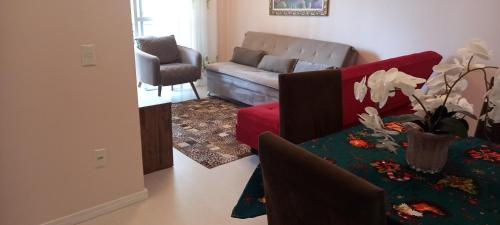 Espaço aconchegante em Criciúma في كريسيوما: غرفة معيشة مع أريكة وطاولة مع زهور