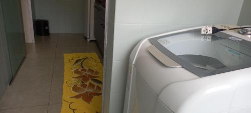 eine Waschmaschine in einem Zimmer mit gelbem Teppich in der Unterkunft Espaço aconchegante em Criciúma in Criciúma