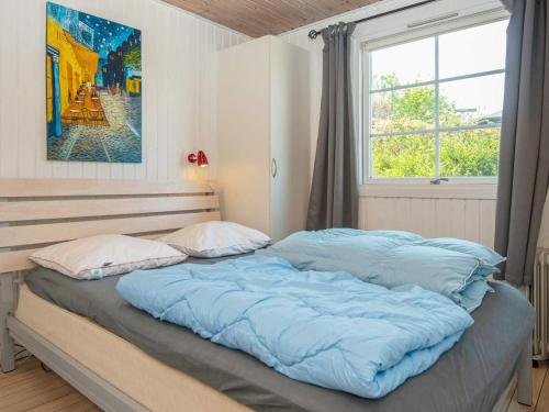 Holiday home Lemvig XXXVIII في ليمفج: غرفة نوم بسرير وملاءات زرقاء ونافذة