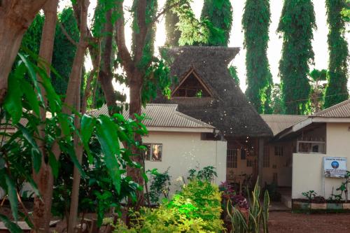 une maison blanche avec un toit noir et des arbres dans l'établissement The Secret Garden Hotel Moshi, à Moshi