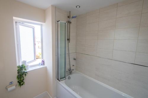 a bathroom with a bath tub and a window at Serene Sands in Felixstowe