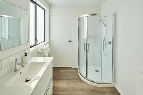 a white bathroom with a shower and a sink at Brand New with Ocean Views in Wellington
