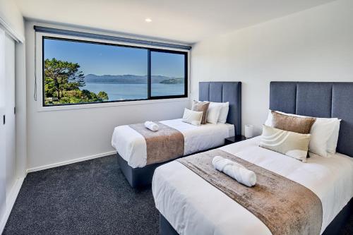 two beds in a room with a large window at Brand New with Ocean Views in Wellington