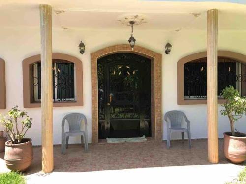 two chairs sitting in front of a front door at Villa calme a tamuda bay médique region de tetuan in M'diq