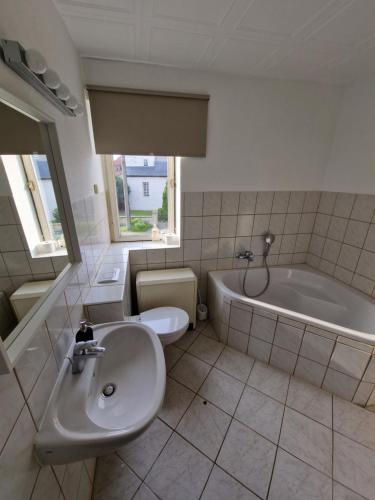a bathroom with a sink and a tub and a toilet at Ferienhaus Jena - Teamwork Holiday House 