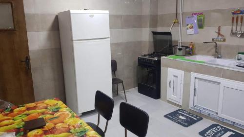 uma cozinha com uma mesa e um frigorífico branco em Très belle appartement em Constantina