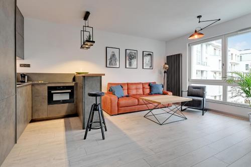 a living room with an orange couch and a table at Sleepy3city Apartments Batorego 9 in Gdynia