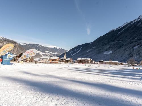 a snow covered field with buildings and mountains at Tauernlodge Krimml 1A in Krimml