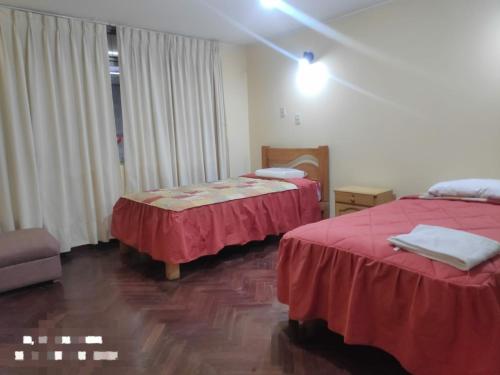 - 2 lits dans une chambre d'hôtel avec des draps rouges dans l'établissement Flying House Hostel, à Arequipa