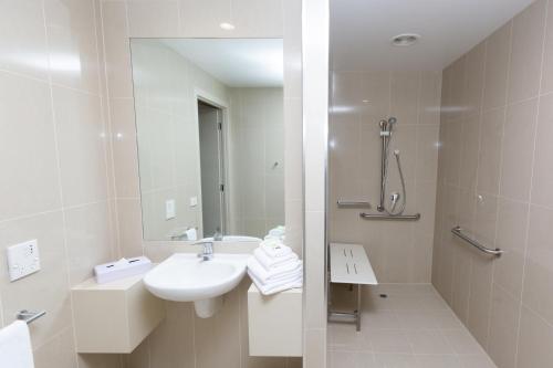 a white bathroom with a sink and a shower at Atlantis Hotel Melbourne in Melbourne