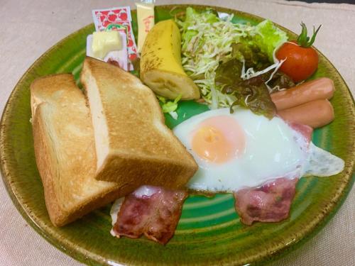 a green plate of food with an egg and toast at Guest House Isa in Motobu