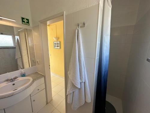 een badkamer met een wastafel en een douche met een handdoek bij Ceu Azul - Elevated villa with stunning views and big garden in Tavira
