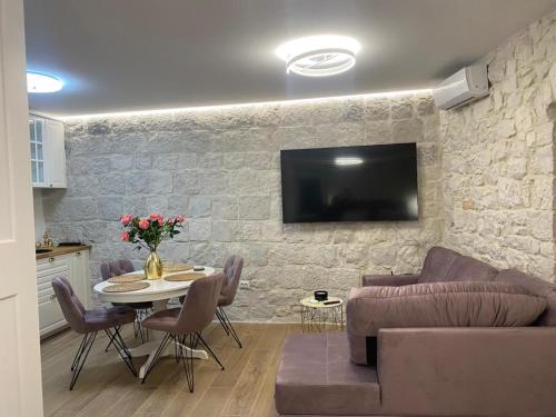 uma sala de estar com uma mesa e uma televisão numa parede de pedra em Garma em Slatine