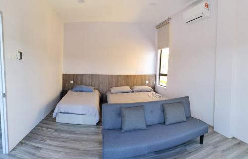 a bedroom with two beds and a blue couch at MersingFirstFloor丰盛港二楼民宿 in Mersing