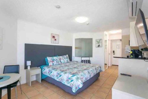 a bedroom with a bed and a table and a kitchen at Alex Resort Studio Small Ocean View in Alexandra Headland