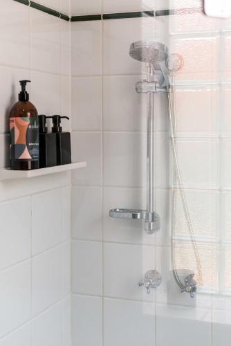 a shower in a bathroom with a white tiled wall at City Edge Home From Home in Keswick