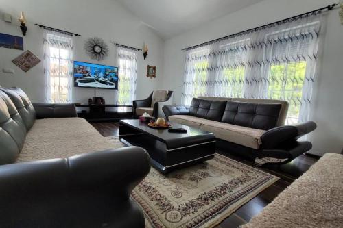 a living room with black leather furniture and windows at Amazing Villa with pool nearby Shtime - Ferizaj in Ferizaj