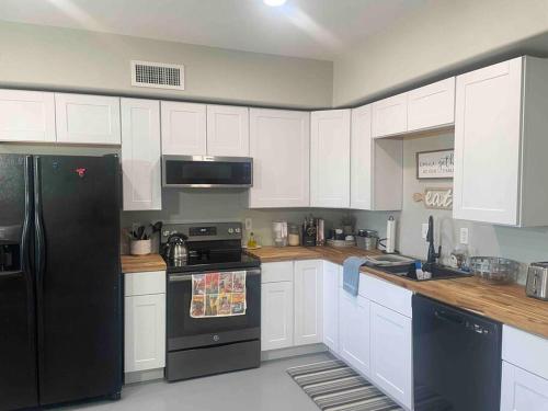 a kitchen with white cabinets and a black refrigerator at Desert Ranch Home 3 Bedroom + Equine Facility in Vail