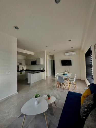 a living room with a couch and tables and a kitchen at Torre Q Mazatlán - Departamento cerca del malecón de Mazatlán in Mazatlán