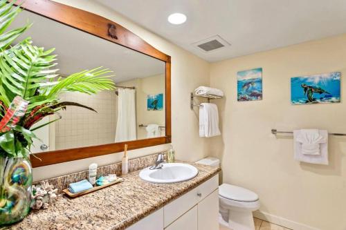 a bathroom with a sink and a toilet and a mirror at Islander Resort Oceanfront # 149 in Kapaa