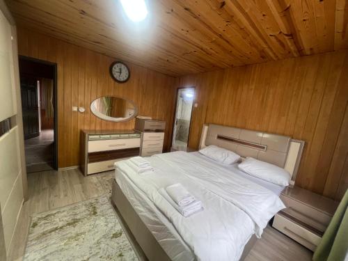 1 dormitorio con 1 cama y reloj en la pared en Cay Suite, en Uzungöl