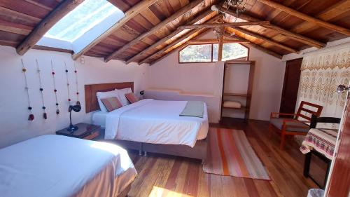 1 dormitorio con 2 camas en una habitación con suelo de madera en Luisa en Ollantaytambo