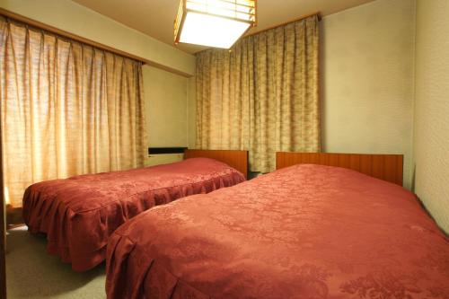 two beds in a room with windows and curtains at Imakuni Ryokan in Takachiho