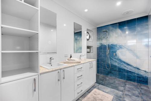 a white bathroom with a sink and a shower at Waters Edge in Frankston